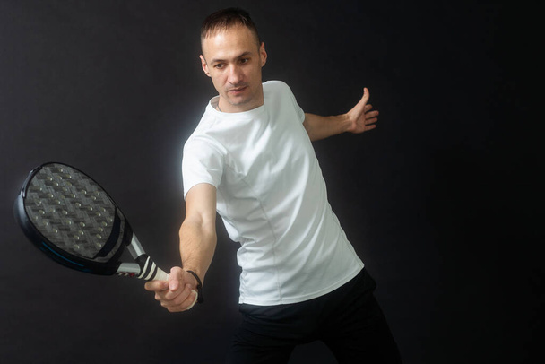 Padel-Tennisspieler mit Schläger in der Hand. Paddeltennis, auf schwarzem Hintergrund. Hochwertiges Foto - Foto, Bild