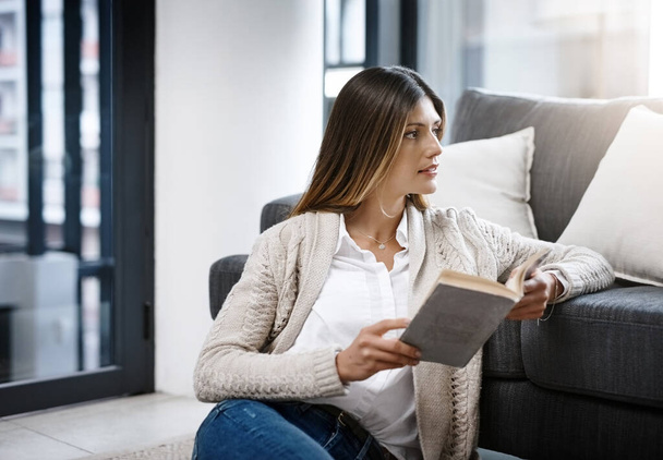 Thinking, home and woman reading book, relax and peace with ideas and hobby in lounge. Person, apartment and girl on the ground, novel and literature with decision and choice with creativity and calm. - Photo, Image