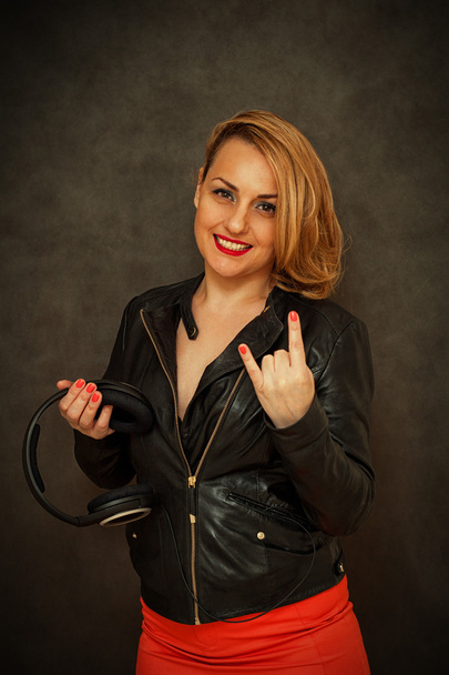 Menina feliz em jaqueta de couro e saia vermelha mostrando polegares cabra de metal
 - Foto, Imagem