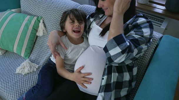 Gyermek szeretetteljes ölelés a várandós anya, ölelése meg nem született kisöccse otthon kanapén - Fotó, kép