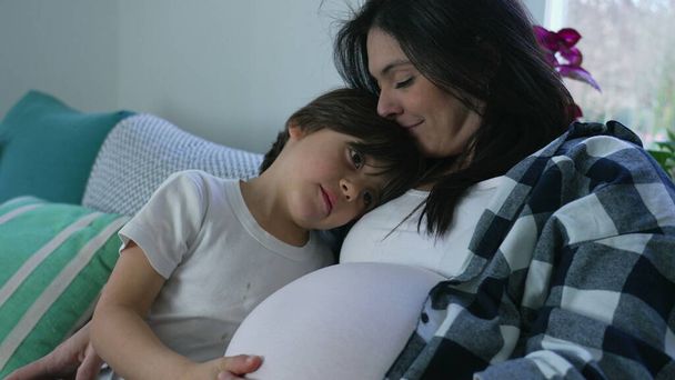 Boy 's Loving Kiss to Unborn Brother, Tierno momento con la madre embarazada en el sofá casero. Tercer trimestre del embarazo, concepto materno - Foto, imagen