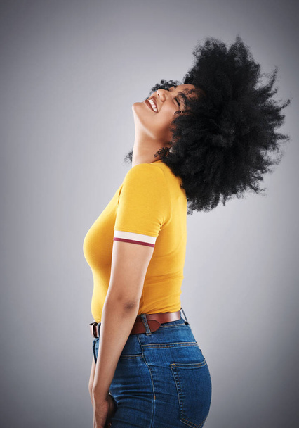 African woman, hair flip and side view for trendy fashion, style or comfort for vibrant, playful or aesthetic. Fashionista, happy and cheerful in studio with jean and bold bright cotton tshirt. - Photo, Image