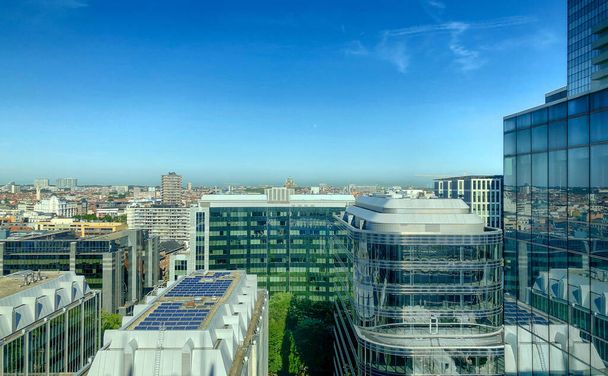 Kuvassa on panoraamanäkymä korkealta näköalapaikalta, joka esittelee Brysselin modernia horisonttia. Painopiste on kestävässä arkkitehtuurissa, kuten aurinkopaneelit koristavat - Valokuva, kuva