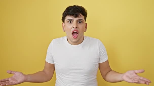 Junger Mann, ehrfürchtig und verängstigt, in weißem T-Shirt, steht auf isoliertem, gelbem Wandhintergrund, den Mund vor Überraschung und Ungläubigkeit zusammengekniffen, die Emotionen deutlich ins Gesicht gemalt - Filmmaterial, Video
