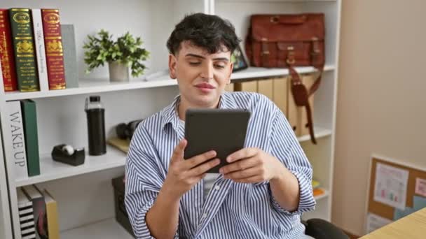 Um jovem adulto sorri ao usar um tablet em um ambiente de escritório moderno, exalando um ar confiante e profissional. - Filmagem, Vídeo