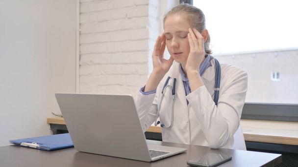 Femme médecin ayant mal à la tête tout en travaillant sur ordinateur portable - Photo, image