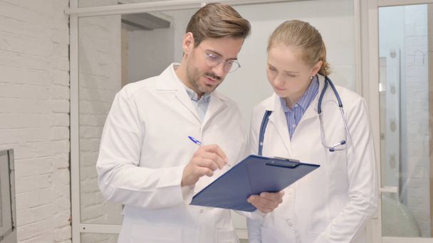 Senior Male Doctor Discussing Medical Report with Female Doctor - Photo, Image
