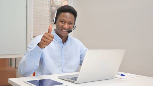 Daumen hoch von Afrikaner mit Headset mit Laptop im Call Center - Foto, Bild