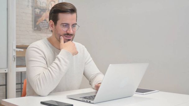 Hombre de mediana edad haciendo chat de vídeo en el ordenador portátil en la oficina - Foto, imagen