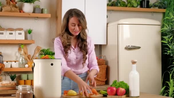 Жінка переробляє органічні відходи шляхом компостування пілінгів овочів на кухні - Кадри, відео