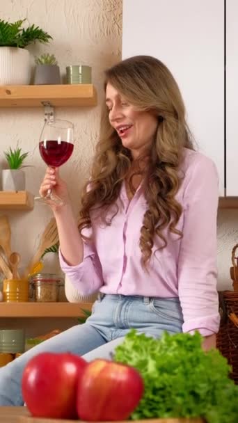 Mulher bebendo um copo de vinho tinto e dançando na cozinha. Verical - Filmagem, Vídeo