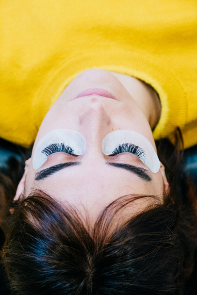 Függőleges kép fiatal nőről hosszú szempillákkal egy szépségszalonban. Szempilla hosszabbítási eljárás. Csukott szemmel. Fénymásolási hely - Fotó, kép