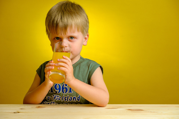 Gelukkig jongetje met glas sinaasappelsap. - Foto, afbeelding