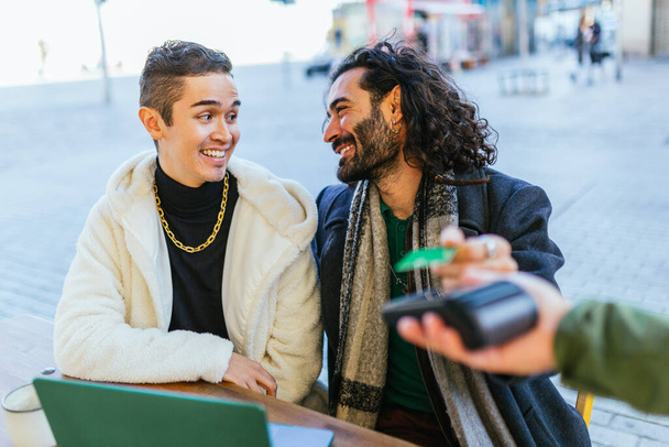 Fröhliche lgbtq Partner teilen einen freudigen Moment, während sie in einem Outdoor-Café sitzen - Foto, Bild
