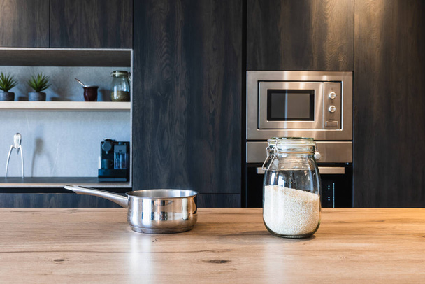 Стильна кухня з темними дерев'яними шафами, приладами з нержавіючої сталі та гладким посудом - Фото, зображення