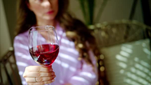 Γυναίκα στροβιλίζεται ένα ποτήρι κόκκινο κρασί στο φως της ημέρας - Πλάνα, βίντεο