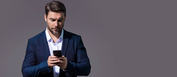 Man using mobile phone isolated over studio background. Man in suit using smart phone cellphone for calls, social media, mobile app. Guy talking on the phone. Banner for header, copy space - Фото, зображення