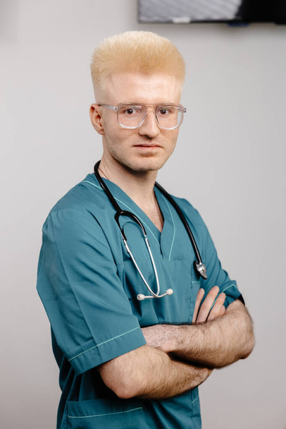 Ein männlicher Gesundheitsexperte in einem grünen Peeling-Anzug ist mit einem Stethoskop um den Hals abgebildet, bereit, medizinische Versorgung zu leisten. - Foto, Bild