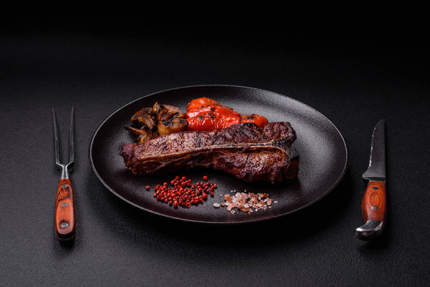 Finom szaftos marhahús steak sóval, fűszerekkel és fűszernövényekkel sötét beton alapon - Fotó, kép