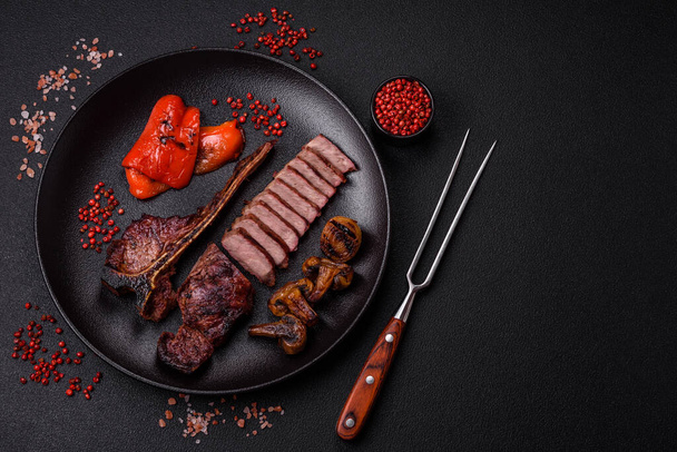 Delicious juicy beef tbone steak with salt, spices and herbs on a dark concrete background - Photo, Image