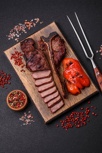 Finom szaftos marhahús steak sóval, fűszerekkel és fűszernövényekkel sötét beton alapon - Fotó, kép