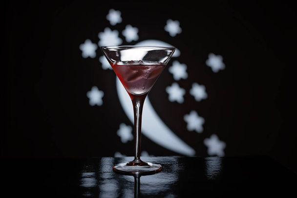 Stemware, Martini ποτήρι γεμάτο με κοκτέιλ Bacardi, που σε ένα φόντο μισοφέγγαρο και αστέρια. Επιτραπέζια σκεύη ιδανικά για το σερβίρισμα αλκοολούχων ποτών με στυλ - Φωτογραφία, εικόνα