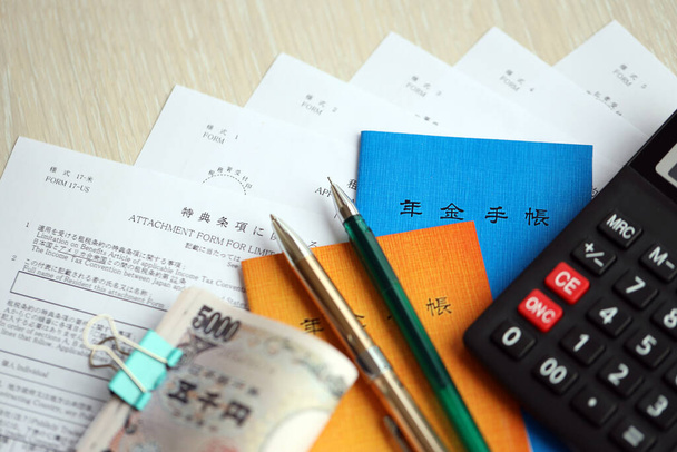 Японські буклети пенсійного страхування на столі з єнськими грошовими рахунками, ручкою і калькулятором на столі крупним планом - Фото, зображення