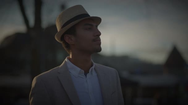 Modieuze jonge knappe man draagt een hoed en casual kleding in de stad - Video