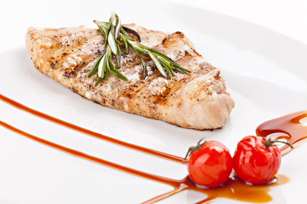 A piece of  grilled fish garnished cherry tomatoes and sprig of  - Photo, Image