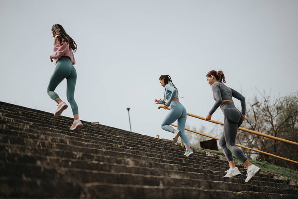 Outdoor-Fitnesskonzept mit jungen Frauen, die gemeinsam Treppen hochlaufen, um Gesundheit und Teamwork zu präsentieren - Foto, Bild