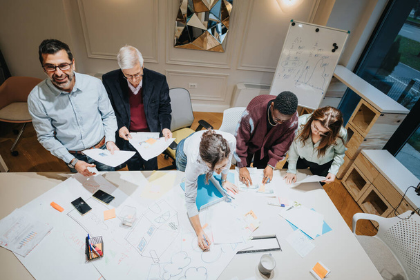 Een dynamisch team van multigenerationele collega 's uit het bedrijfsleven die samen op kantoor samenkomen, brainstormen en strategiseren. - Foto, afbeelding