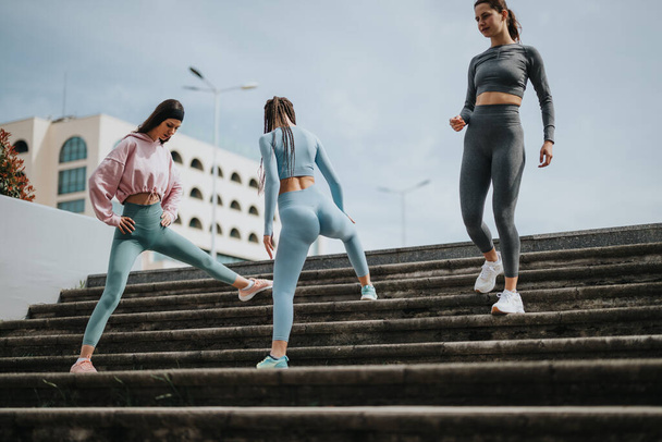 Активные женщины в спортивной одежде поднимаются по ступеням в городской среде, демонстрируя здоровье и фитнес. - Фото, изображение