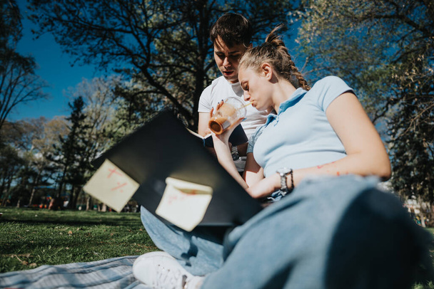 Estudiantes de secundaria enfocados que estudian juntos al aire libre, compartiendo ideas para un proyecto de clase en el campus. - Foto, Imagen