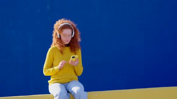 Κοκκινομάλλα νεαρή γυναίκα ακούει χαλαρωτική μουσική με πολύχρωμο μπλε αντίγραφο χώρο. - Πλάνα, βίντεο