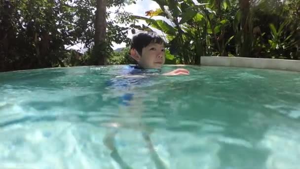 mignon garçon nager dans la piscine, surface de l'eau avec la lumière du soleil - Séquence, vidéo