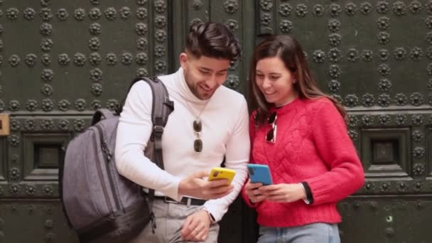 Z-sukupolven pari, joka käyttää älypuhelimia ja hymyilee ulkona, teknologiassa ja sosiaalisen median konsepteissa. Laadukas FullHD kuvamateriaalia - Materiaali, video