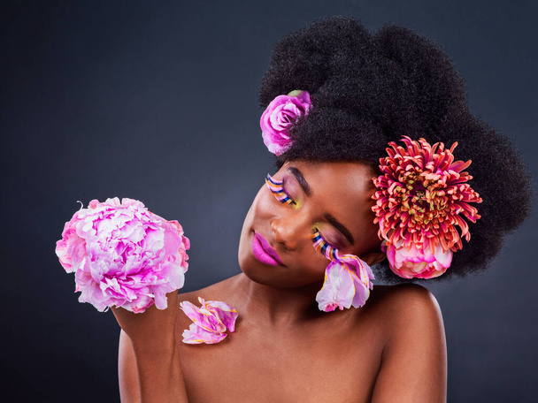 Black woman, flowers and studio with natural makeup in confidence with skincare, gentle and plant. Nature, rose and peonies for health with wellness for beauty in spring with afro for cosmetic. - Photo, Image