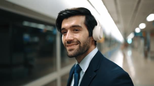 Smart business man calling phone while wearing headphone at train station. Professional executive manager talking to colleague about marketing strategy while waiting for train or subway. Exultant. - Footage, Video