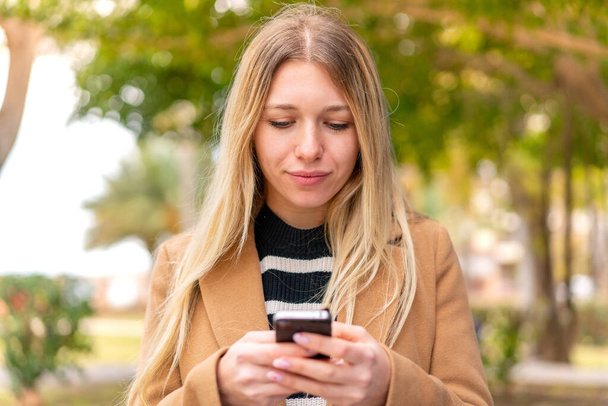 Jovem mulher loira bonita ao ar livre usando telefone móvel - Foto, Imagem