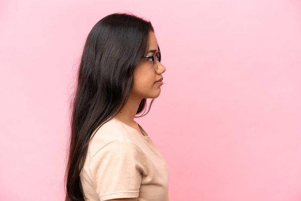 Νεαρή Κολομβιανή απομονωμένη σε ροζ φόντο με γυαλιά - Φωτογραφία, εικόνα