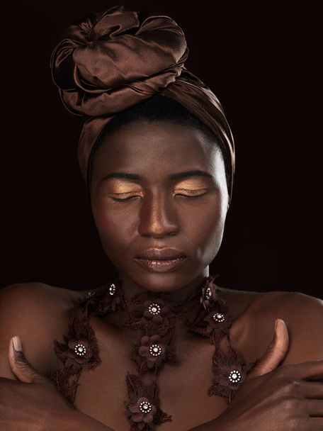 Afrikaanse vrouw, tulband en make-up door donkere achtergrond met elegantie, pose en handen voor de traditionele cultuur. Zwarte koningin, huid en cosmetica in studio met schoonheid, ogen dicht en erfgoed uit Nigeria. - Foto, afbeelding