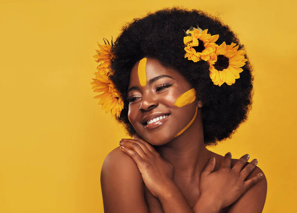 Zwarte vrouw, studio en natuur zonnebloemen voor de lente, natuurlijke huidverzorging en rust met Afrikaans model en afro. Zelfzorg, wellness voor schoonheid met biologische cosmetica, dermatologie op gele achtergrond. - Foto, afbeelding