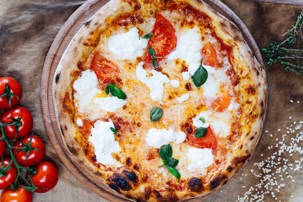 Klasyczna pizza margherita, z prostymi, ale aromatycznymi dodatkami stopionej mozzarelli, aromatycznej bazylii i pikantnym parmezanem - Zdjęcie, obraz