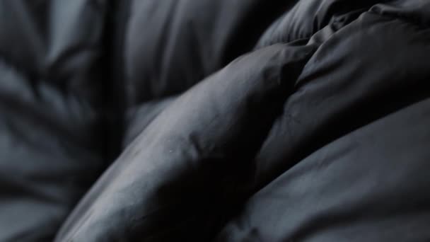 Czarna podpuchnięta kurtka zimowa jako tło z bliska, czarne tło - Materiał filmowy, wideo