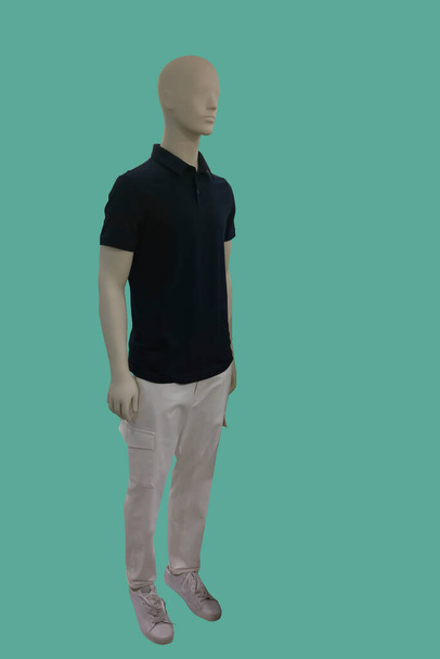 Полное изображение мужского дисплея манекена в футболке с черной шеей поло и белых брюках груза, изолированных на зеленом фоне - Фото, изображение