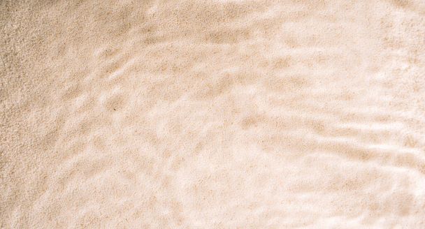 Κίτρινη καθαρή άμμος με κυματιστά σχέδια κάτω από καθαρό νερό. - Φωτογραφία, εικόνα