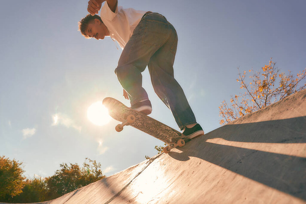 Genç kaykaycı kaykay parkının rampasında sörf tahtasıyla uçar. - Fotoğraf, Görsel
