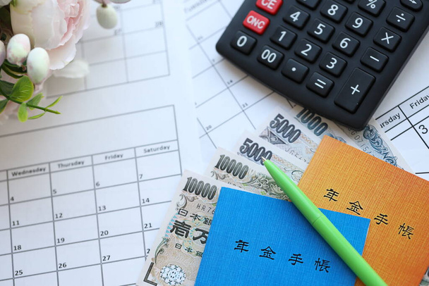 Японські буклети пенсійного страхування на столі з єнськими грошовими рахунками та калькулятором на столі крупним планом - Фото, зображення