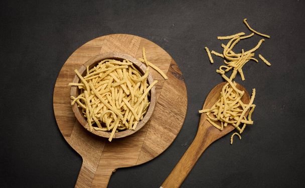 Raw wheat noodles in wooden bowl, top view - Photo, Image