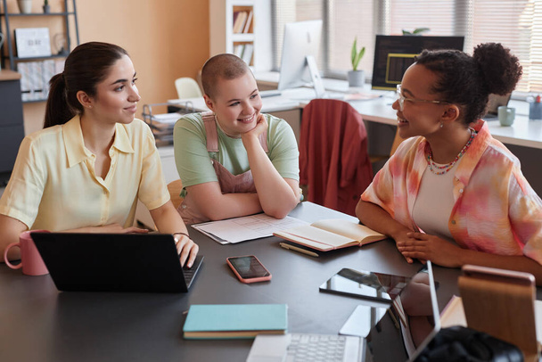 Portrait of three young women at meeting table enjoying work together in office - Photo, Image
